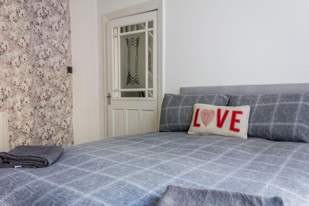 a blue bed with a pillow with the word love on it at Modern 4 Bed House Sleep 7 in Liverpool