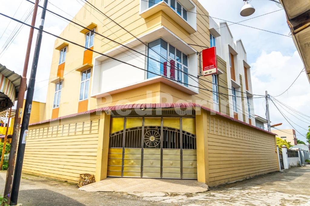 a yellow and white building with a garage at Adam Malik Guesthouse near Regale ICC Medan Mitra RedDoorz in Medan