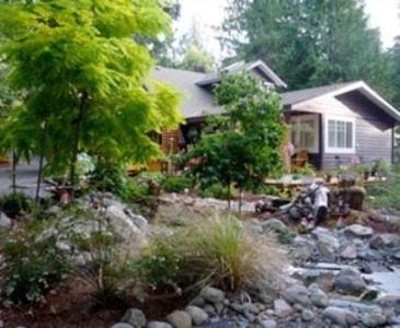a house with a landscaped yard with rocks and a tree at Tea Cozy Bed & Breakfast in Qualicum Beach
