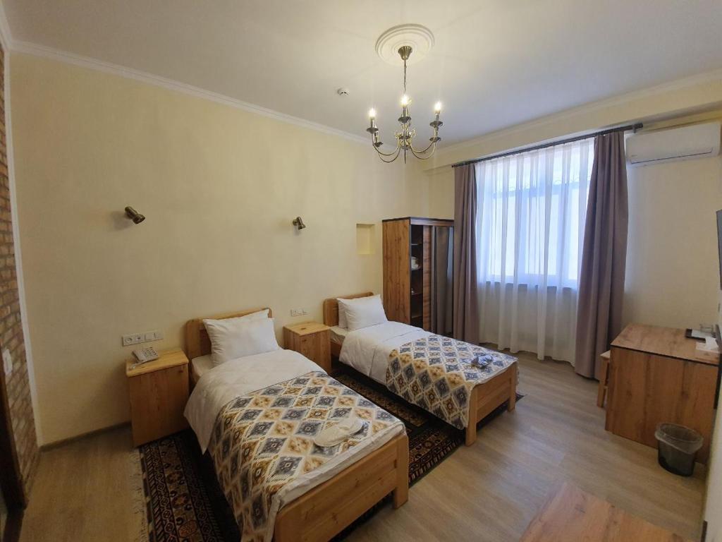 a hotel room with two beds and a chandelier at Chorsu Inn in Tashkent