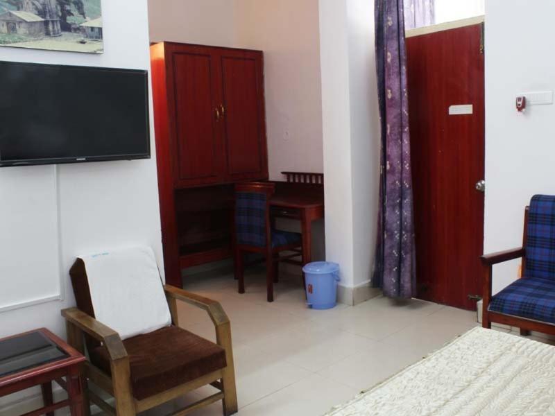 ein Wohnzimmer mit einem Tisch und Stühlen sowie einem TV in der Unterkunft GMVN Guest House Rudraprayag in Kurchhola