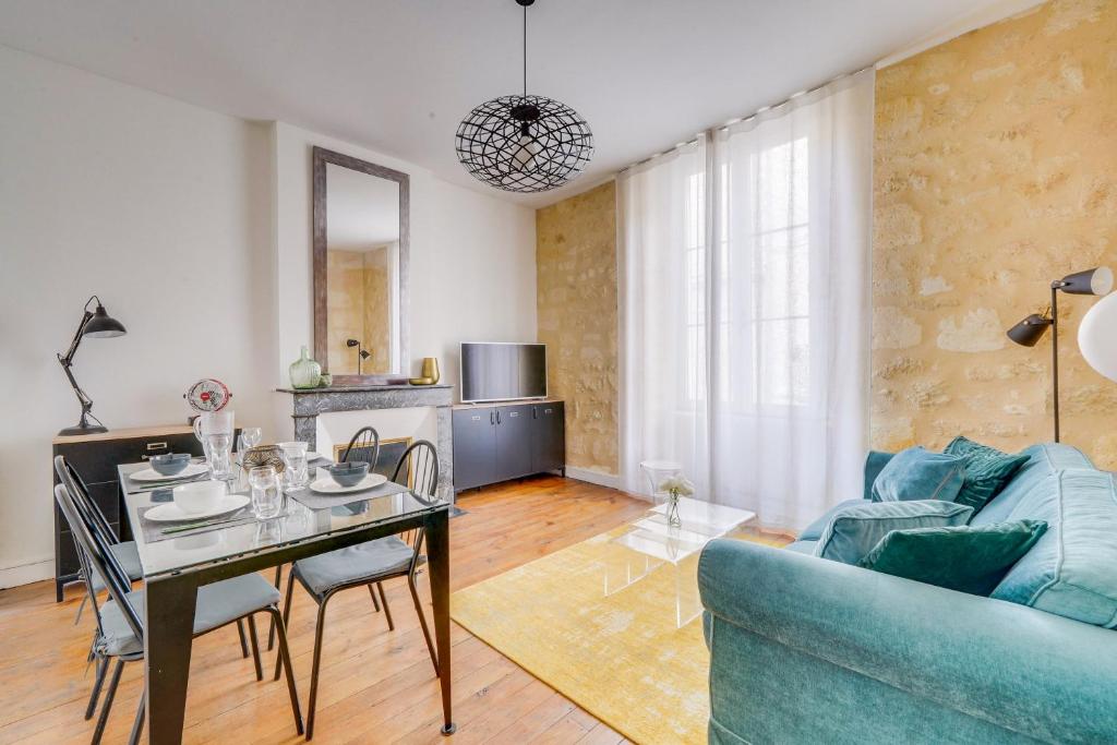 un salon avec une table et un canapé bleu dans l'établissement Chez Jeanne - Appartement Hyper Centre, à Bordeaux