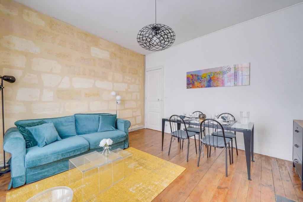 a living room with a blue couch and a table at Chez Jeanne - Appartement Hyper Centre in Bordeaux