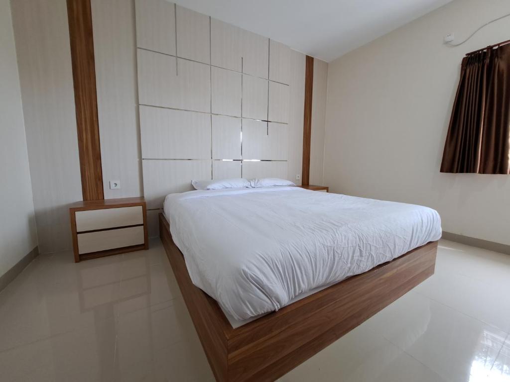 1 dormitorio con 1 cama grande con sábanas blancas en Pillow Guest House, en Balikpapan