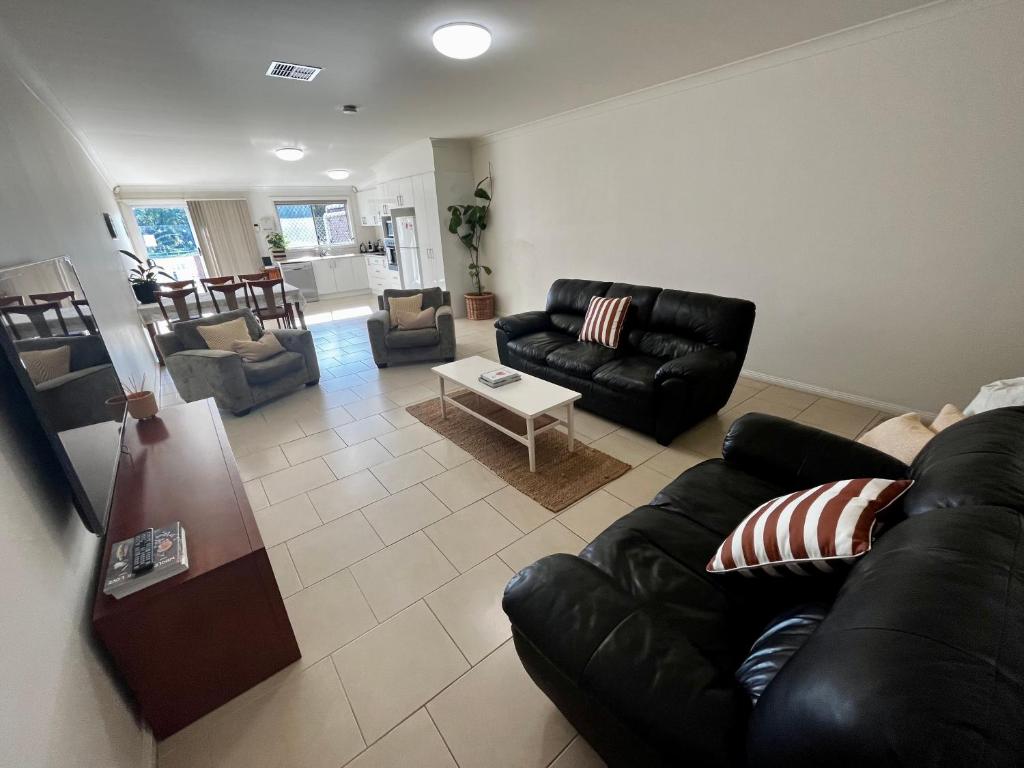 a living room with a black leather couch and chairs at Downtown Narrabri in Narrabri