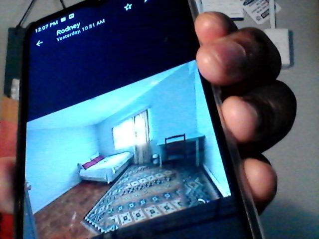 una mano sosteniendo un teléfono móvil con una foto de una sala de estar en Highbury Square Flat, en Ciudad del Cabo