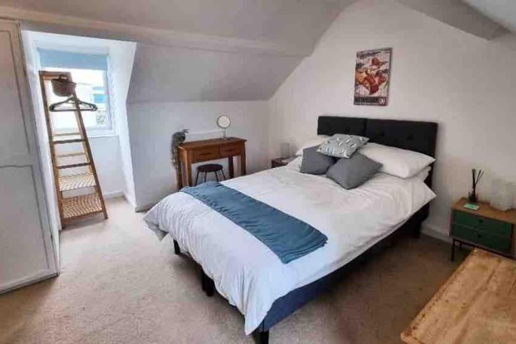 een slaapkamer met een groot bed en een bureau bij Mermaid Cottage Teignmouth by the beach SLEEPS 7 in Teignmouth