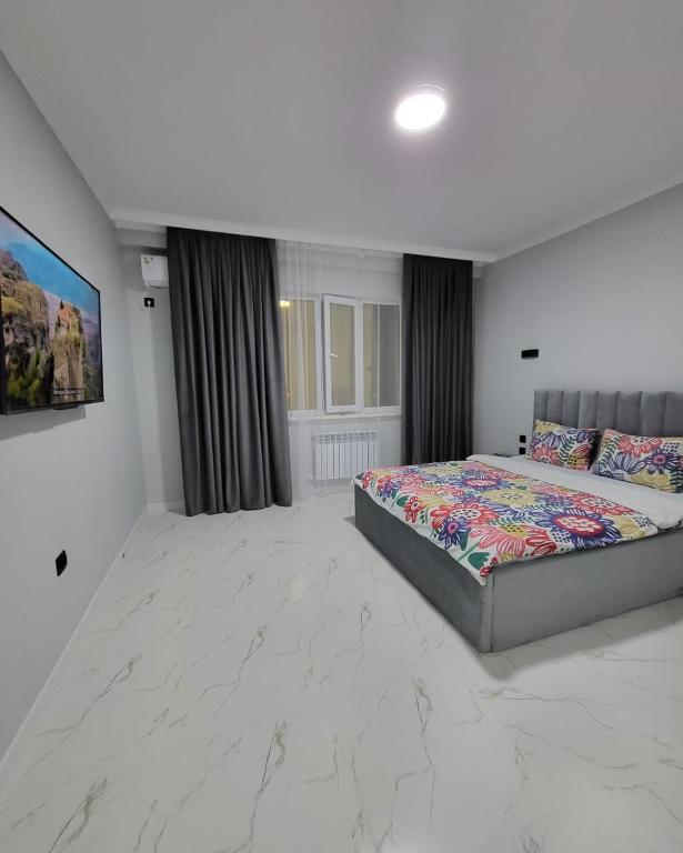 a large bedroom with a bed and a painting on the wall at К7 family in Atyraū