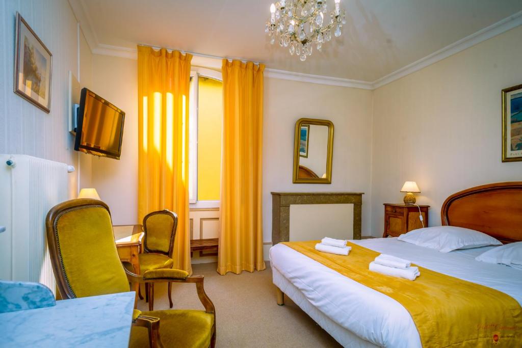 a bedroom with a large bed and a chandelier at Hôtel Continental in Évian-les-Bains