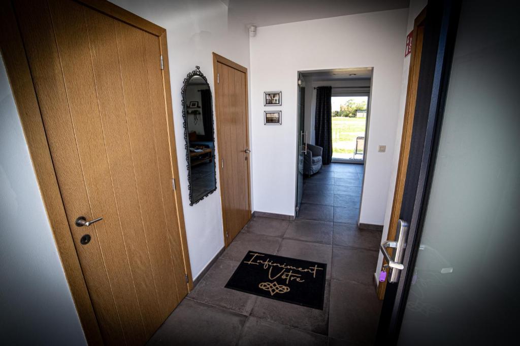 un corridoio con porta e tappetino di benvenuto sul pavimento di Infiniment Vôtre a Onhaye