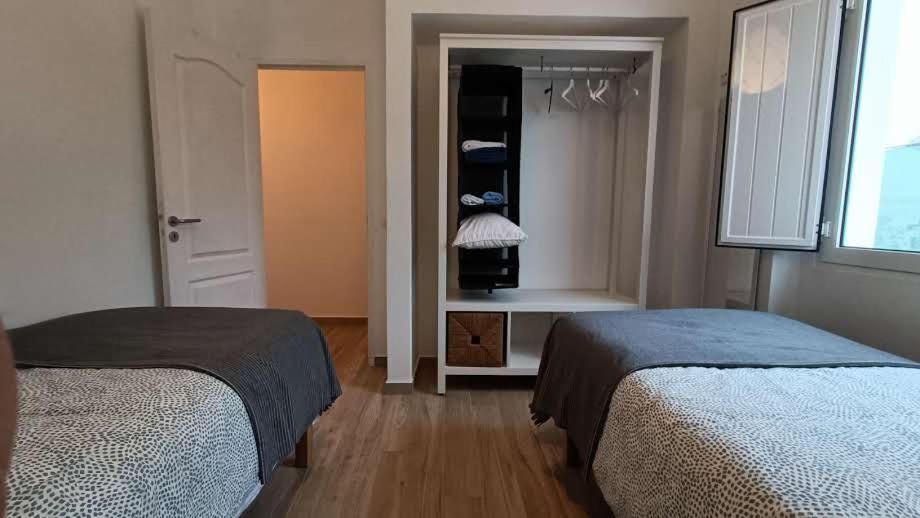 a bedroom with two beds and a closet with a window at Casa do Bairro 21 in Portel