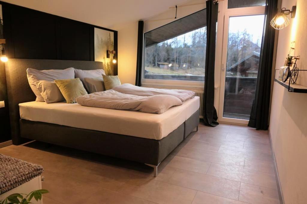 a bedroom with a large bed with a large window at NEST'L Appartements & Zimmer in Mösern