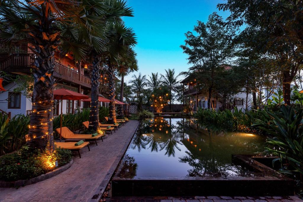 ein Resort mit einem Pool mit Stühlen und Bäumen in der Unterkunft Dontrei Villa Angkor in Siem Reap