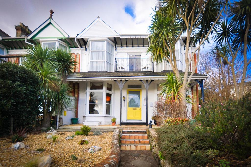 a white house with a yellow door and palm trees at Avron House in Torquay