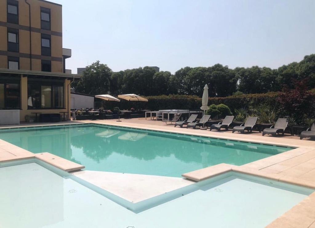 a large swimming pool with chairs and a building at Hotel La Rocca in Nogarole Rocca