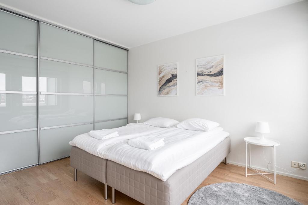 a white bedroom with a large bed with glass walls at 2ndhomes Tampere "Koskenranta" Apartment - Sauna, Rooftop Terrace, Amazing Views & Free Parking in Tampere