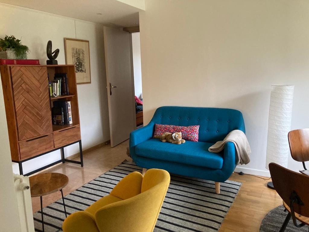 een woonkamer met een blauwe bank en 2 stoelen bij Vue sur jardin, 3 pièces in Parijs
