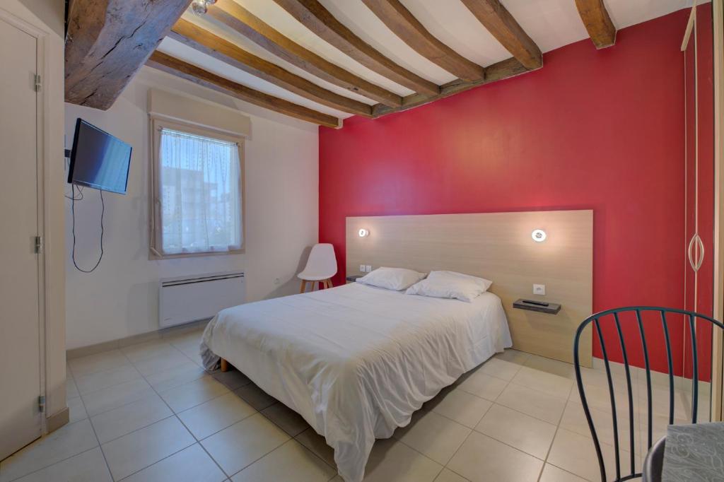 ein Schlafzimmer mit einem weißen Bett und einer roten Wand in der Unterkunft La Petite Maison appartement 1 in Avoine