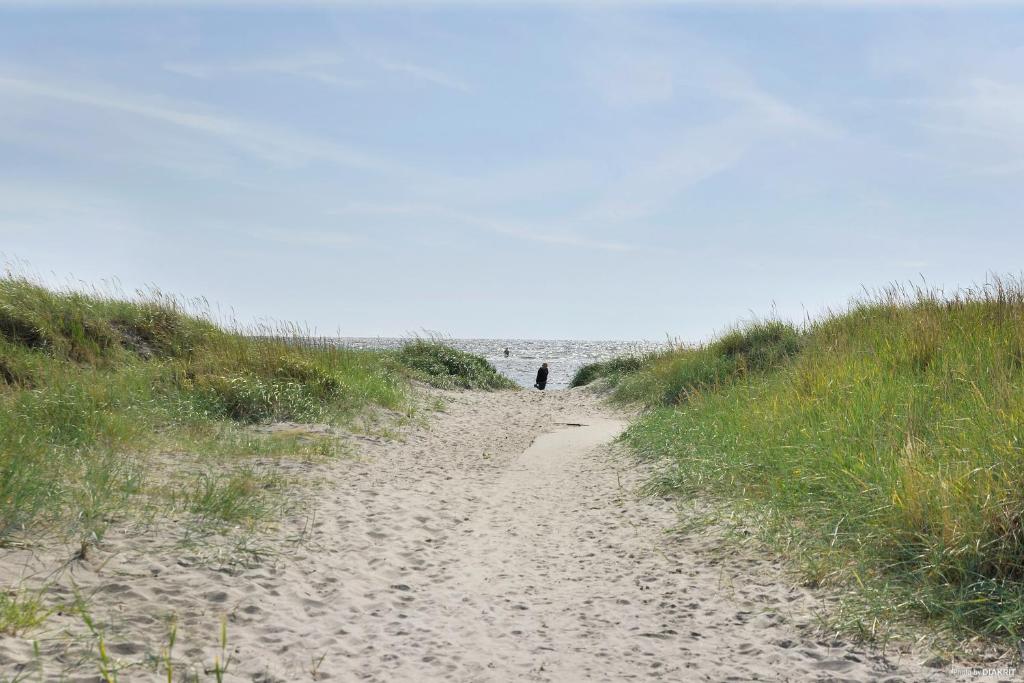 una persona caminando por un camino de arena hacia la playa en First Camp Björkäng-Varberg en Tvååker