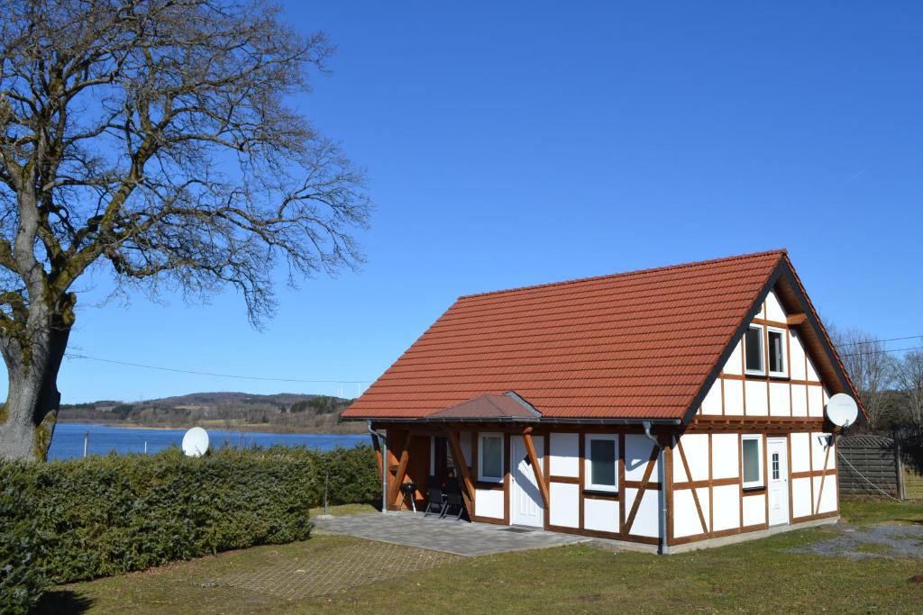 a house with a red roof and a tree at HM - Ferienhaus 2 Deluxe Krombachtalsperre Westerwald exklusive verbrauchte NK in Driedorf