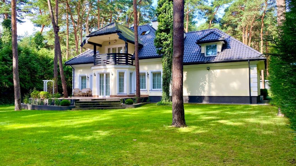 une maison avec une pelouse verte devant elle dans l'établissement 4 Bedroom Peaceful Relaxation with outdoor wood-fired sauna and spa, à Magdalenka