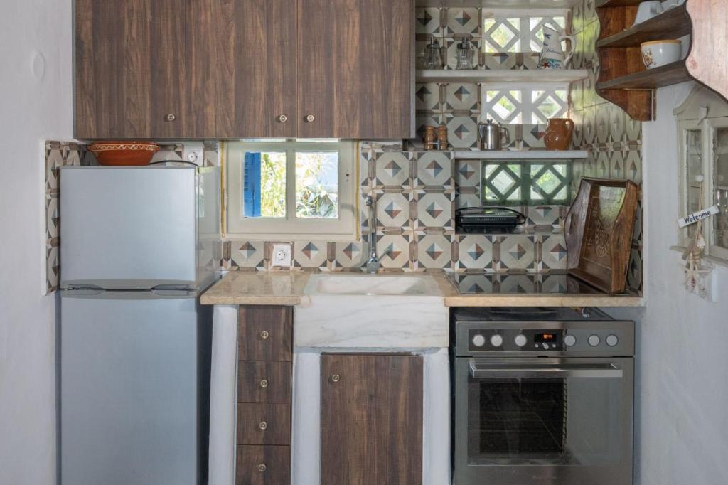 a kitchen with wooden cabinets and a white refrigerator at Alexandros by the Beach - Serifos in Livadakia