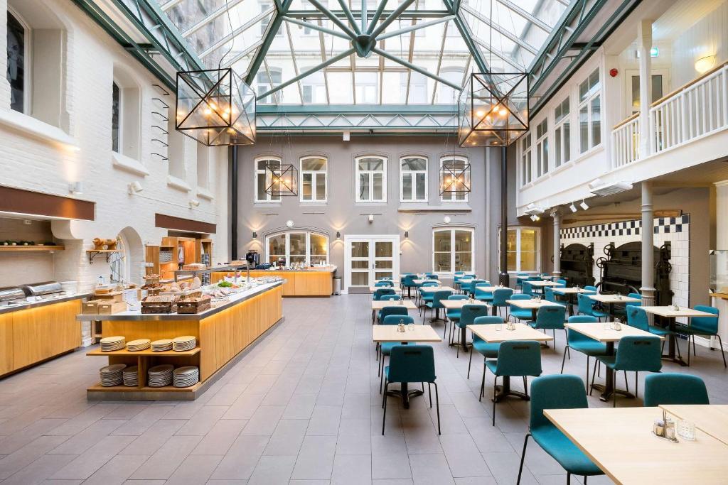 un restaurant avec des tables et des chaises et un plafond en verre dans l'établissement Best Western Plus Hotel Bakeriet, à Trondheim