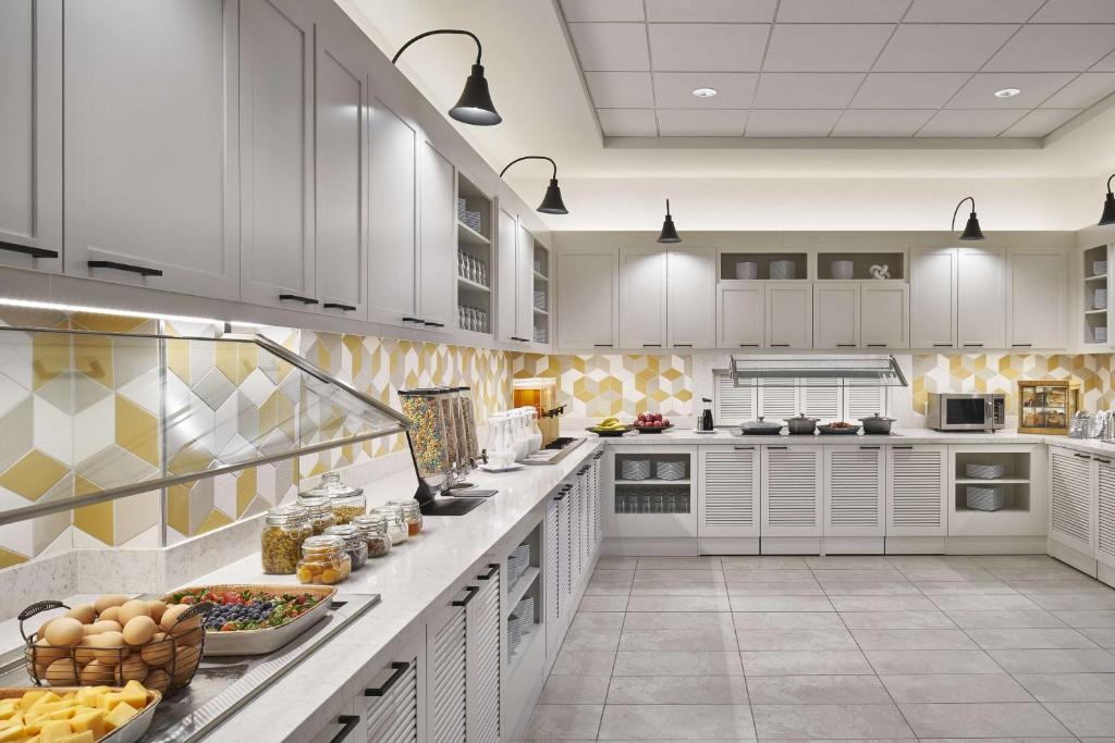 a large kitchen with white cabinets and food on a counter at Hyatt Place Wilmington Riverfront in Wilmington
