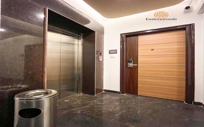 um hall de entrada de um elevador com uma lata de lixo de metal em frente a uma porta em Easternwoods Hotels em Bangalore
