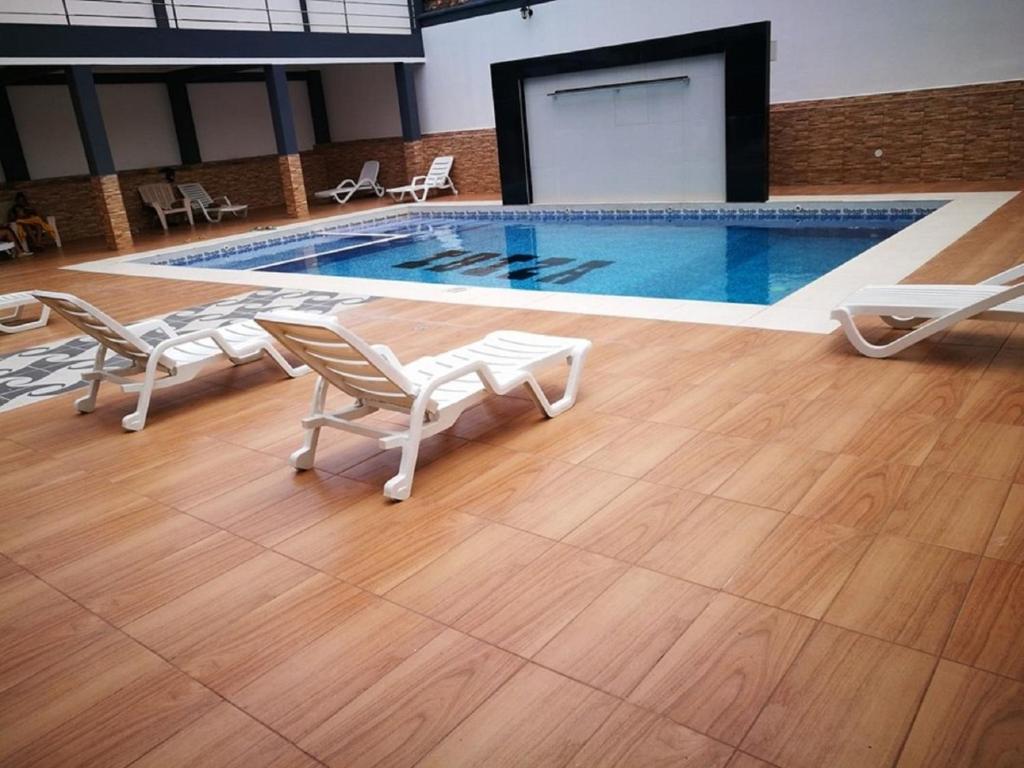 a swimming pool with chairs and a table and a screen at Hostal Ibiza in Santa Cruz de la Sierra