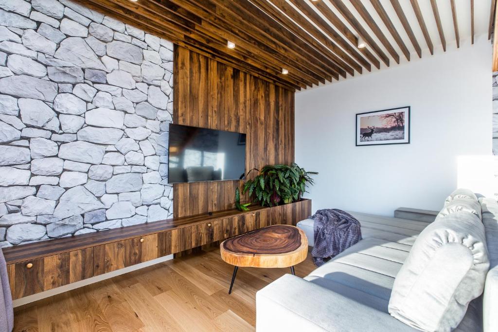 Cozy living area featuring wood-paneled TV wall, stone accent, live-edge coffee table, plush gray sofa.