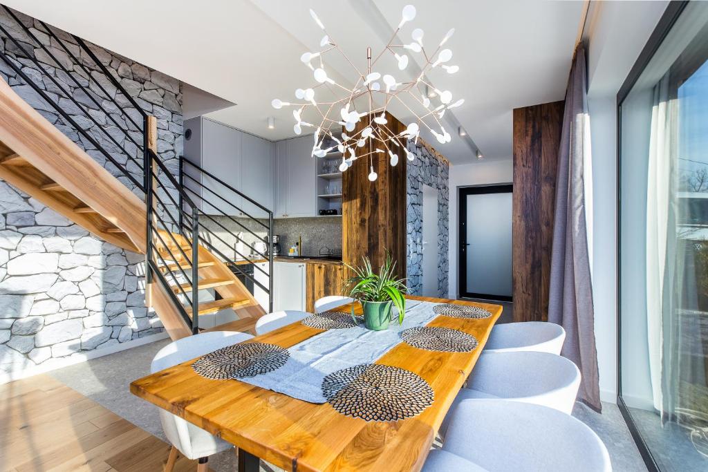 Wooden dining table set with placemats and plant centerpiece, staircase and stone wall behind.