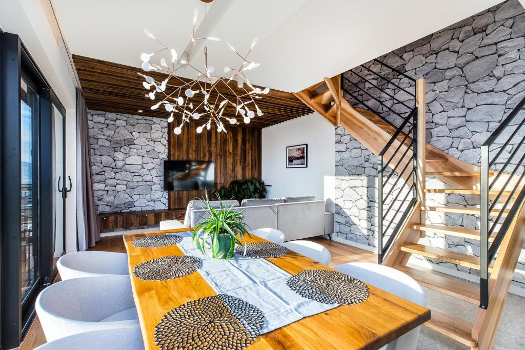 Open-plan dining and living area featuring wooden table, chandelier, sofa and staircase.