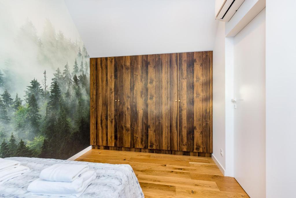 Wooden built-in wardrobe against wall, hardwood floor and misty forest mural to the left.