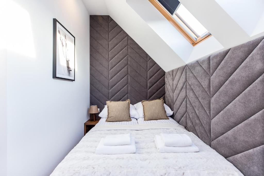 Centered bed framed by grey chevron headboard and skylight, neutral pillows and folded towels.