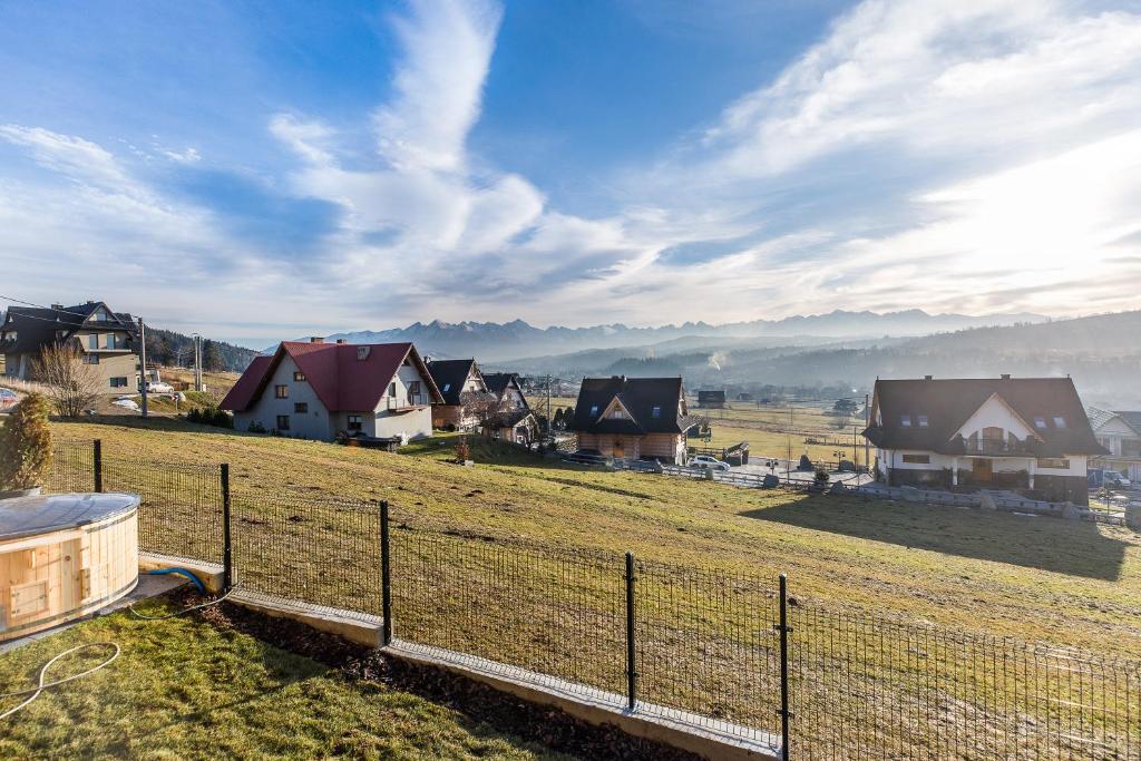 Wide valley view from fenced yard showing houses, rolling fields and distant mountain range under morning sky.