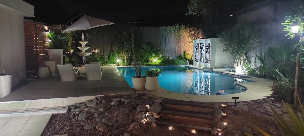 una piscina con plantas en un patio trasero por la noche en Posada El Alamo Mendoza en Mendoza