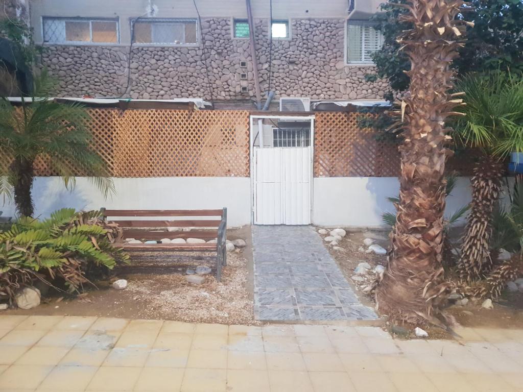 a bench in front of a building with a tree at Nitra rooms in Neve Zohar