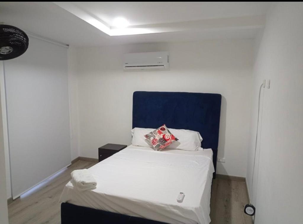 a small bedroom with a bed with a blue headboard at Apartamentos Dreams TR in Santa Marta