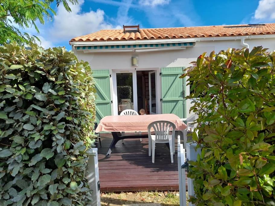een tafel en stoelen op een houten terras voor een huis bij Maisonnette à deux pas de la plage dans résidence calme in La Tranche-sur-Mer