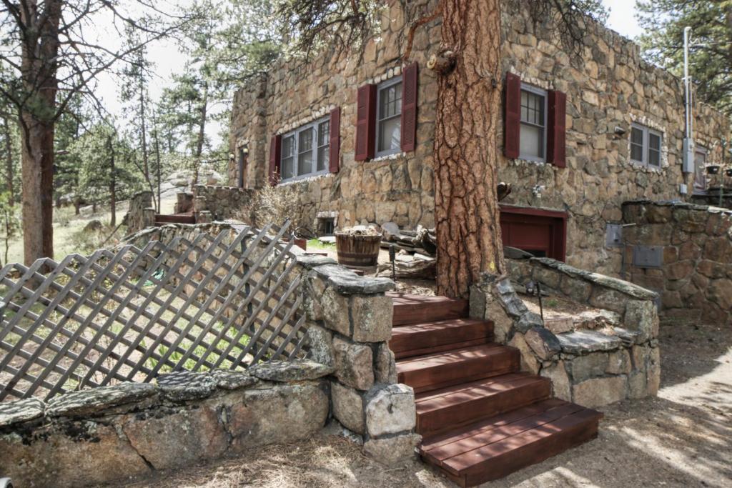un antiguo edificio de piedra con escaleras junto a un árbol en Stonehaven Home by Rocky Mountain Resorts- #3384, en Estes Park