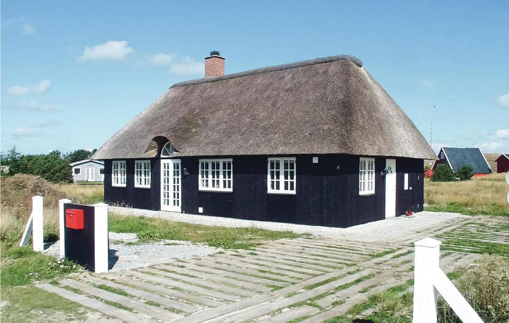 una casa negra con techo de paja en un campo en Awesome Home In Fan With 1 Bedrooms, en Sønderho