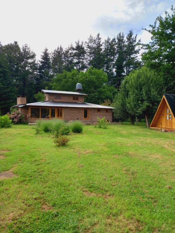 una casa en un patio con un campo de hierba en Hostel Chacra La Templanza en El Hoyo