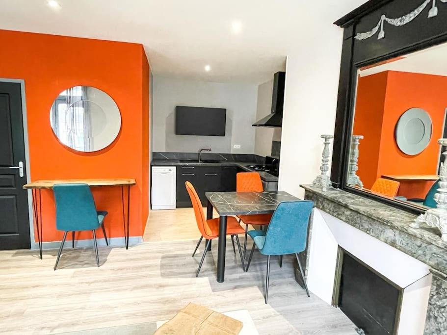 a dining room with a table and chairs and an orange wall at Joli appartement hyper-centre in Alençon