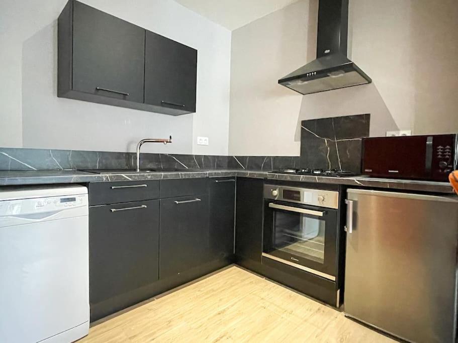 a kitchen with stainless steel appliances and black cabinets at Joli appartement hyper-centre in Alençon