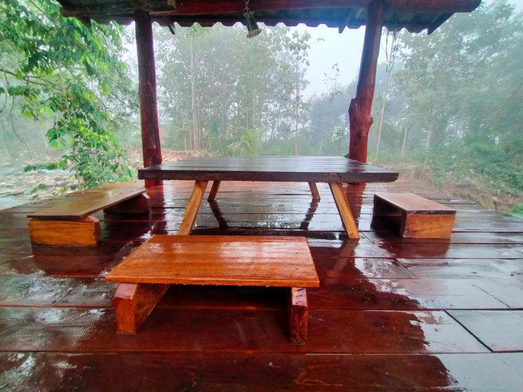 a wooden table and benches in the rain at Huean Him Pan Homestay เฮือนฮิมปานโฮมสเตย์ in Ban Mae Pan