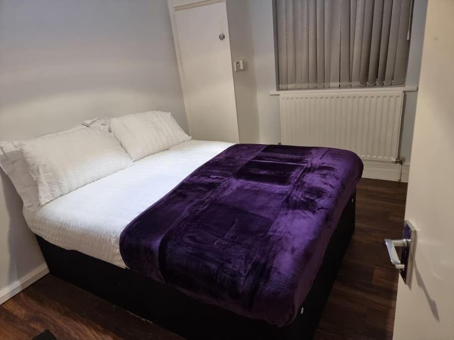 a bed with a purple blanket on top of it at Cosy 3 bed Apt/contractors/families/free parking in Birmingham