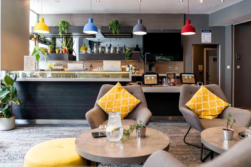 un restaurante con 2 sillas, mesas y una barra en Heeton Concept Hotel - Kensington London en Londres