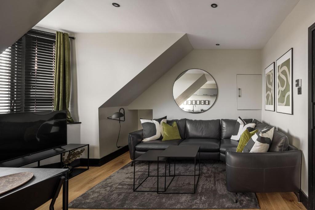 een woonkamer met een zwarte bank en een spiegel bij Broomhill Loft in Aberdeen