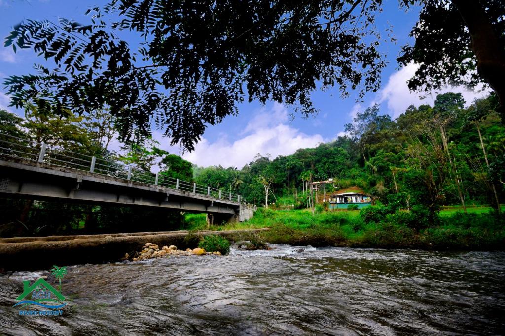 a bridge over a river next to a forest at ACH RIVER RESORT in Rattota